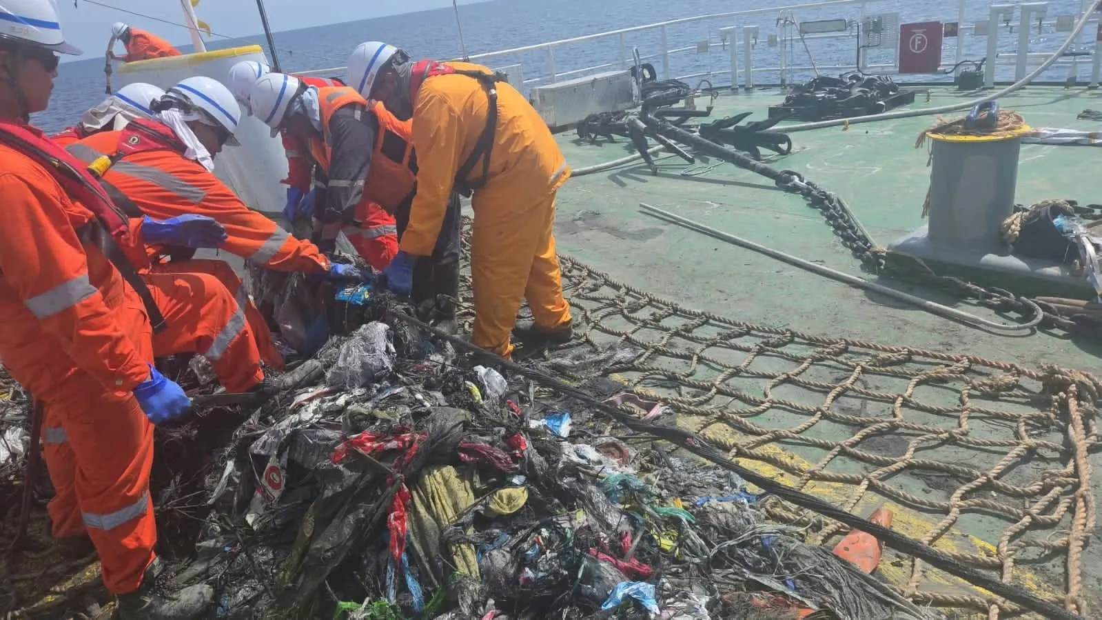 Submarine cable recovery: crew removing debris from the cable by hand